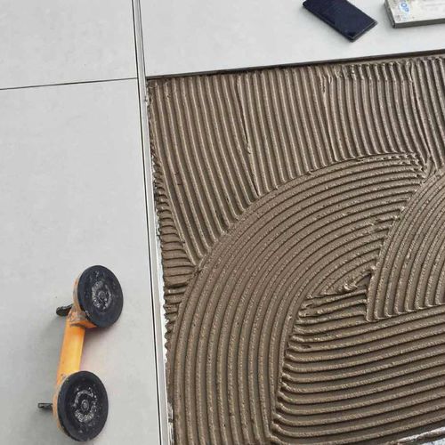 Auftragen von Fliesenkleber oder Fliesenmörtel, der mit einer Zahnkelle gekämmt wurde, um Fliesen zu verlegen.